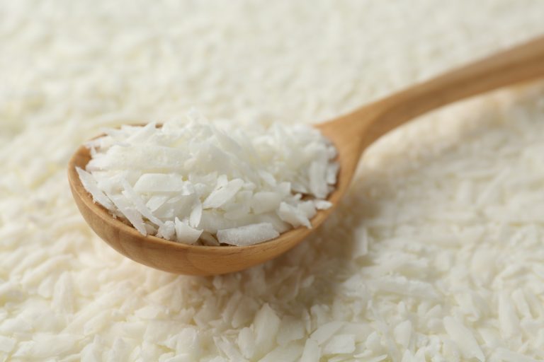 White soy wax flakes and spoon, closeup